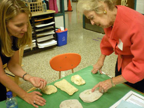 Two women examine clay sculptures