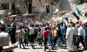 Civilians and Free Syrian Army fighters chant slogans as they walk past damaged buildings during a protest against President Bashar al-Assad in Aleppo on 14 June. Photograph: Reuters Handout/Reuters (The Guardian)