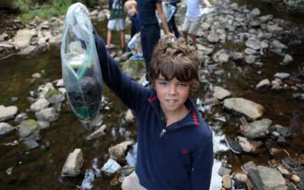 Boy holds up trash collected in a creek