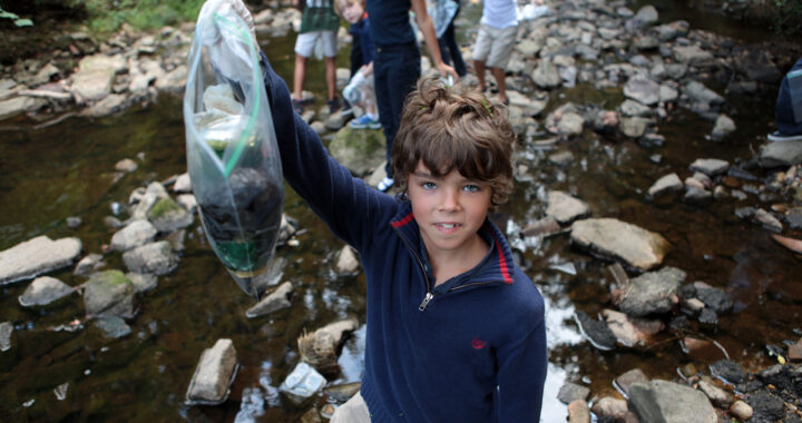 Boy holds up trash collected in a creek