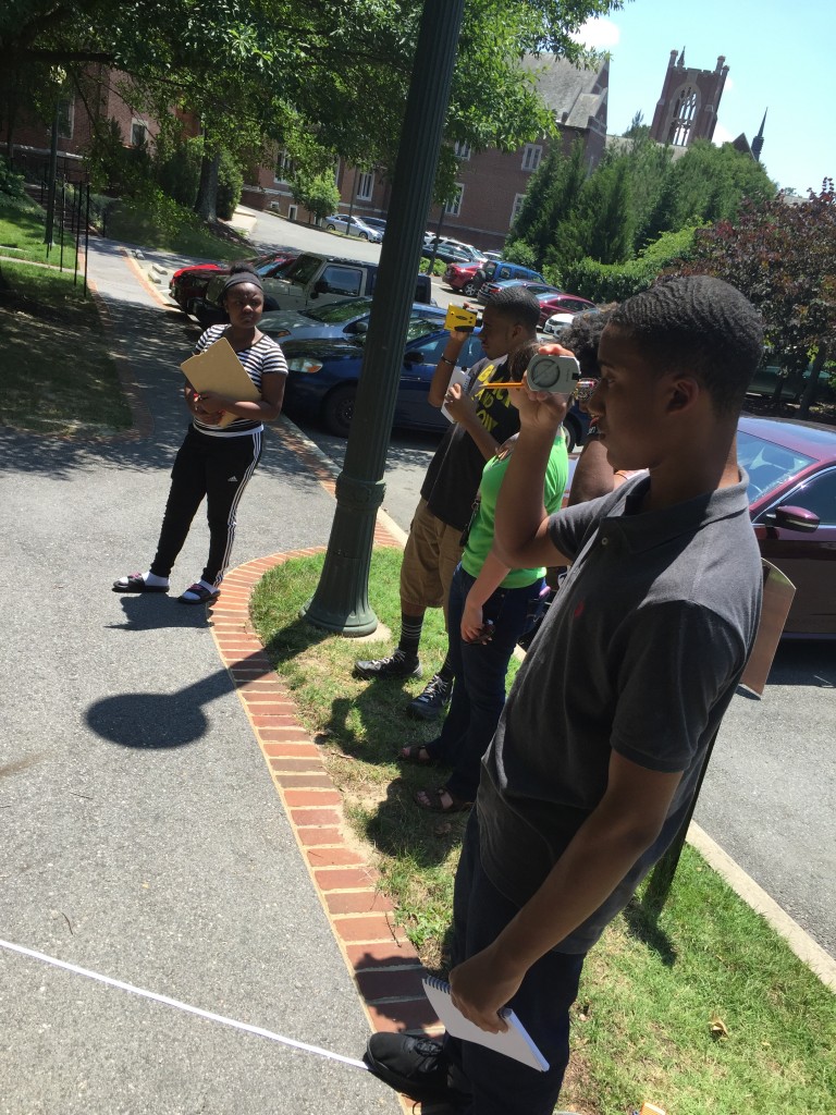 Students using the laser range finder, after having measured their distance from the tree using the tape measure on the ground. 